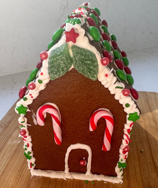 Gingerbread house with candy cane details on a wooden surface
